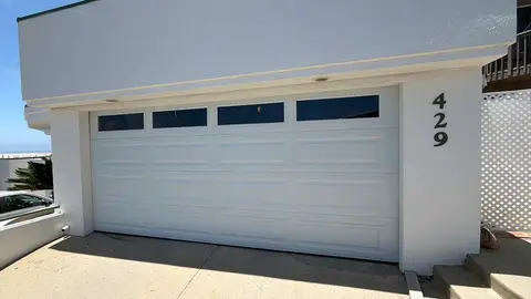 White double-car garage door with top glass window panels installed at a Los Angeles home, why choose MSB Garage Door Repair